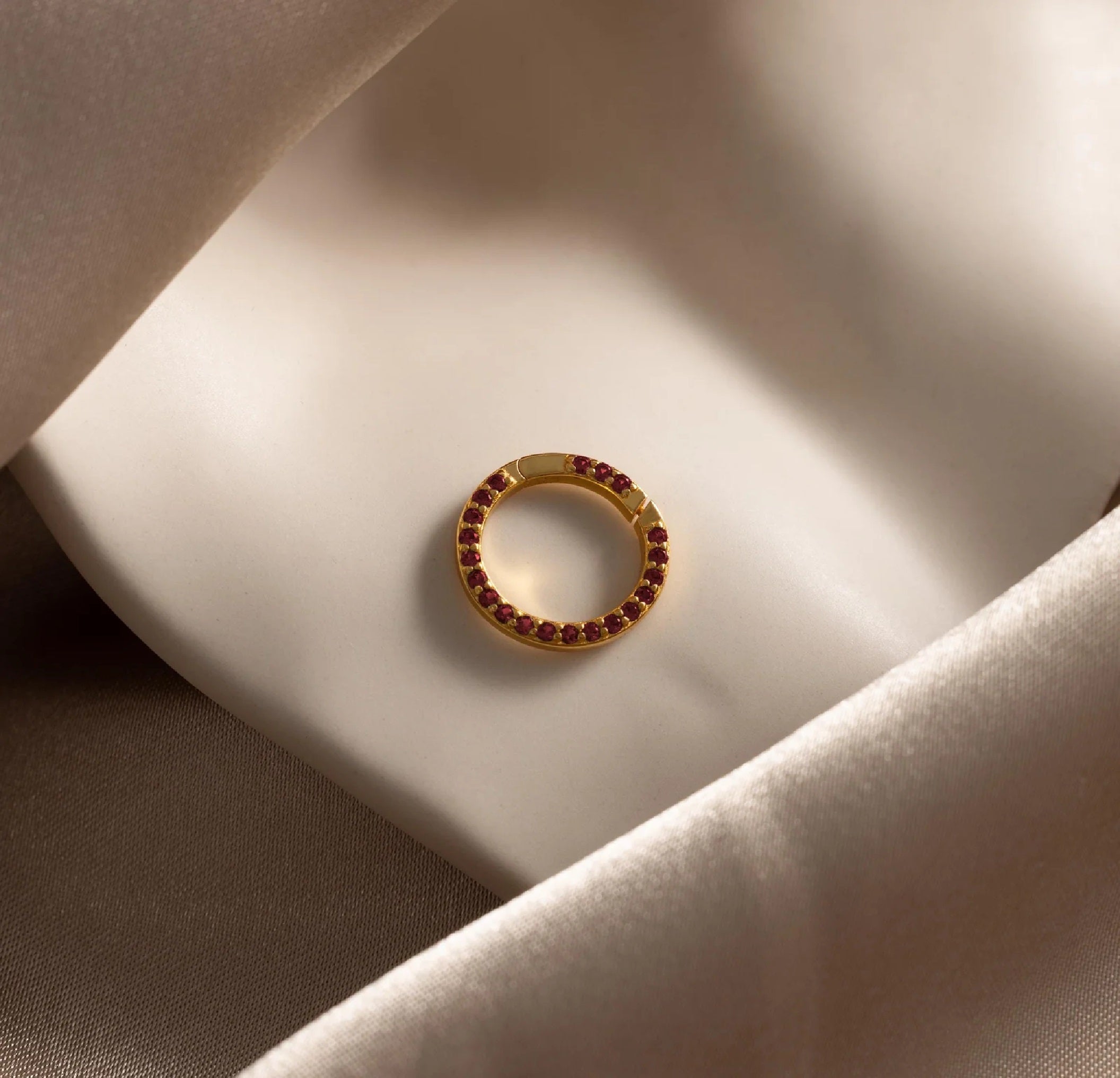Gold ring with red gemstones on a soft fabric surface